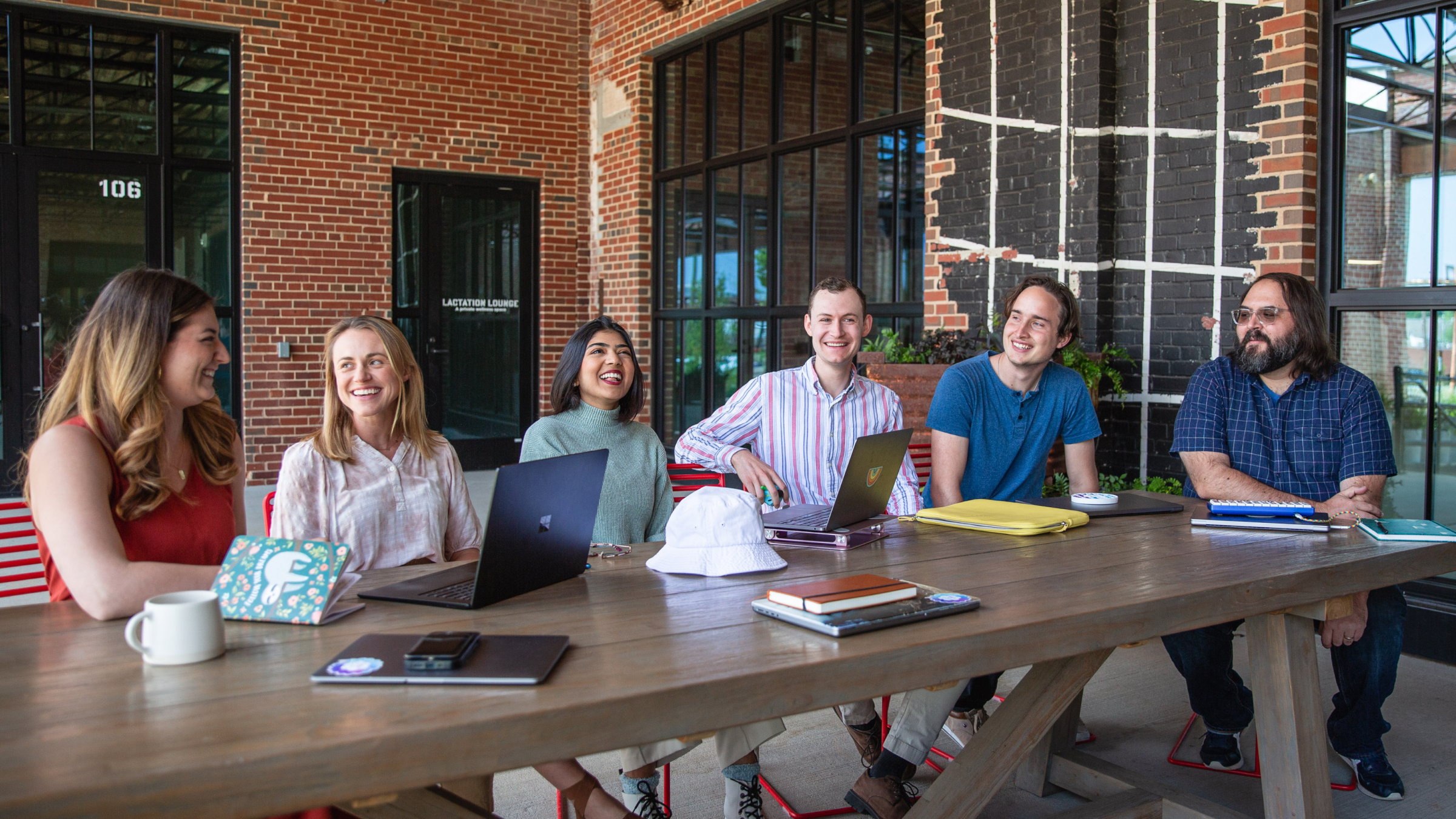 Group of people sitting around a wooden table.