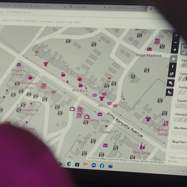 A computer screen displays a detailed digital map with various shops and landmarks labeled along Jomo Kenyatta Avenue, including icons for fashion, services, and points of interest.